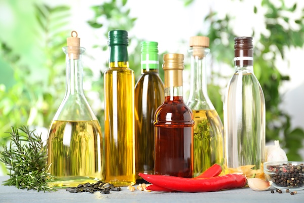 Different sorts of cooking oil in bottles and ingredients on white wooden table